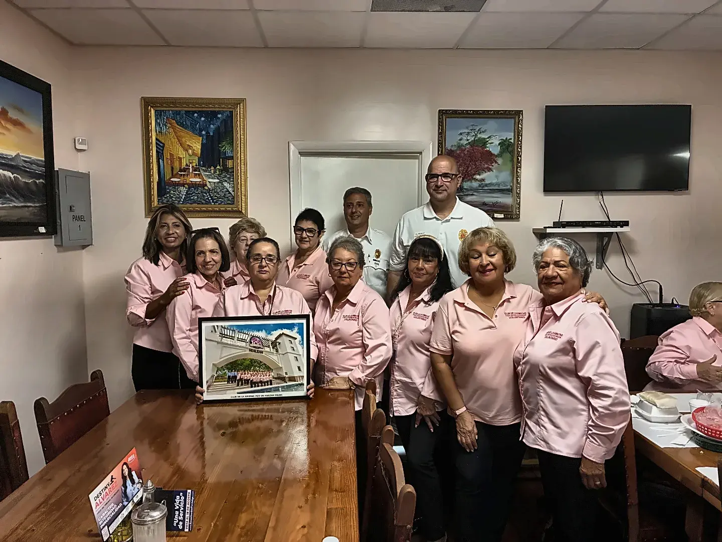Club de la Amistad volunteers holding a framed photograph of the Hialeah gate